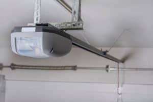 A close-up view of an automatic garage door opener mounted on the ceiling, with metal rails and brackets securing the device in place for convenient garage access.